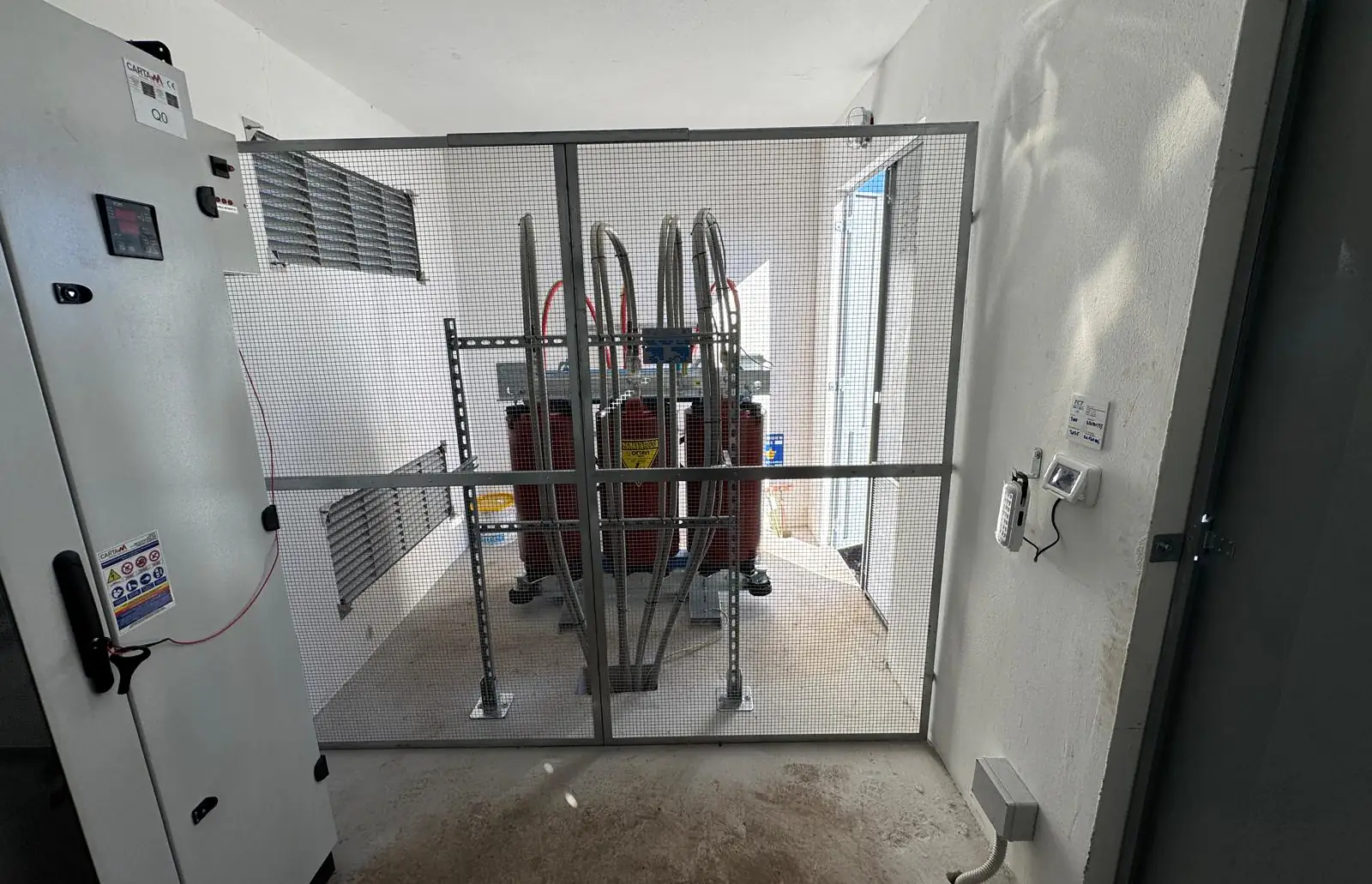 Interno di una cabina: quadro di bassa tensione a sinistra, trasformatori dietro la rete di protezione